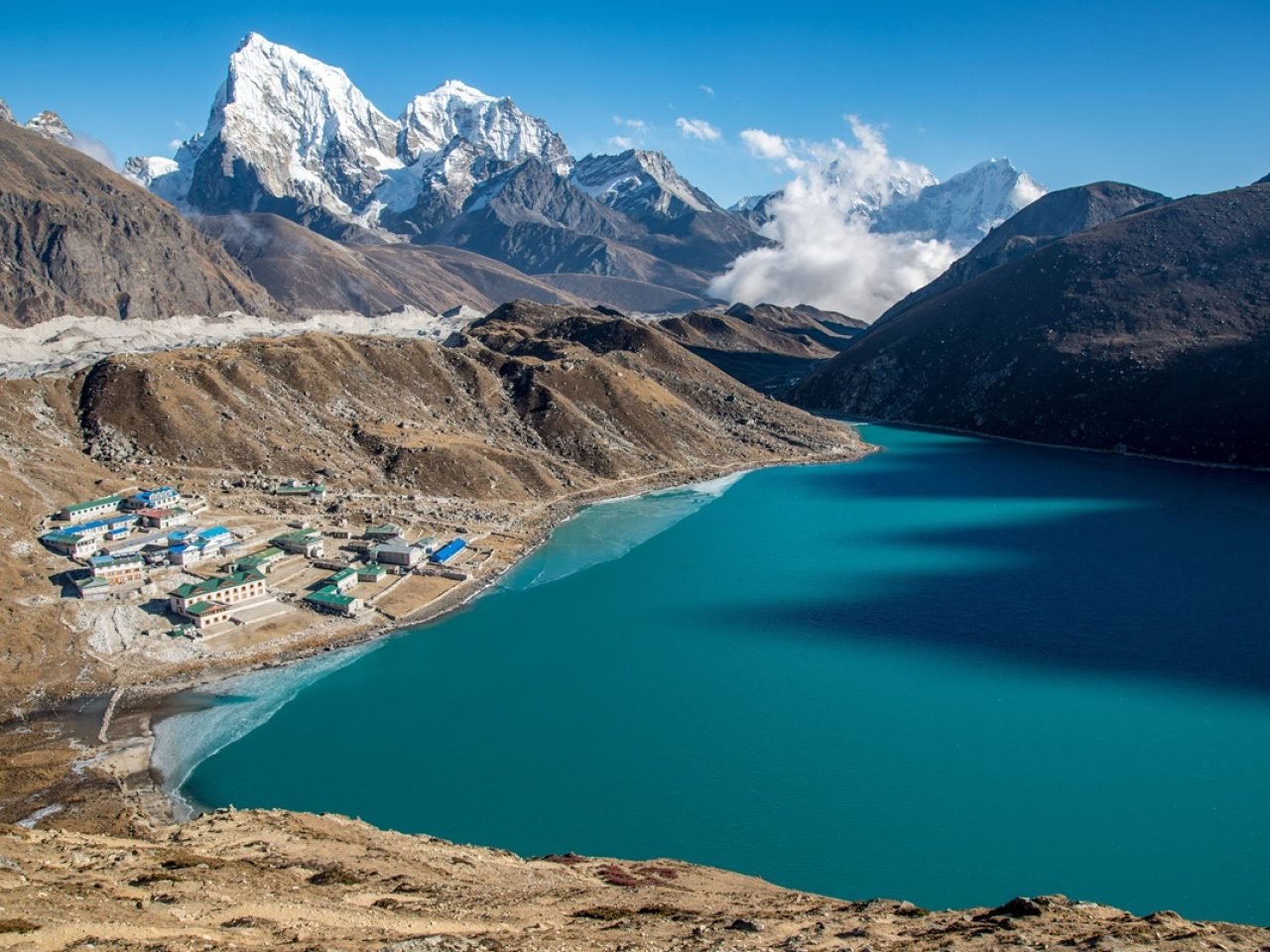 A high shot of a small town near a blue body of water surrounded by beautiful mountains.